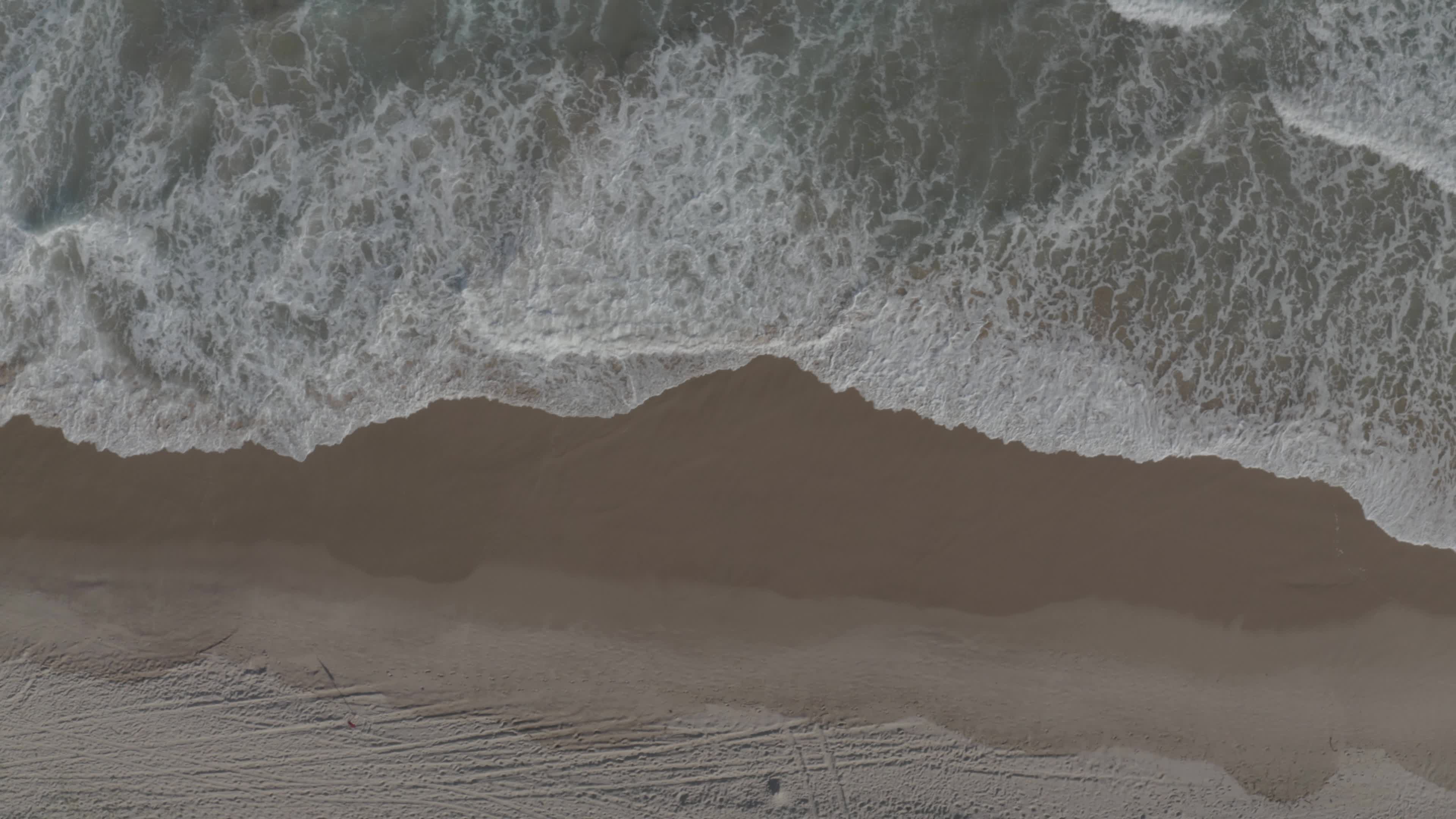 top view of waves gently breaking on beach sand