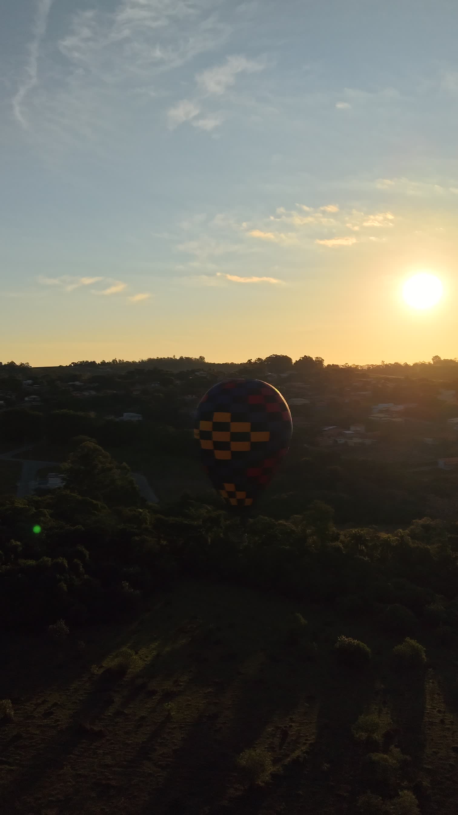 Balão colorido sobrevoando ao pôr do sol