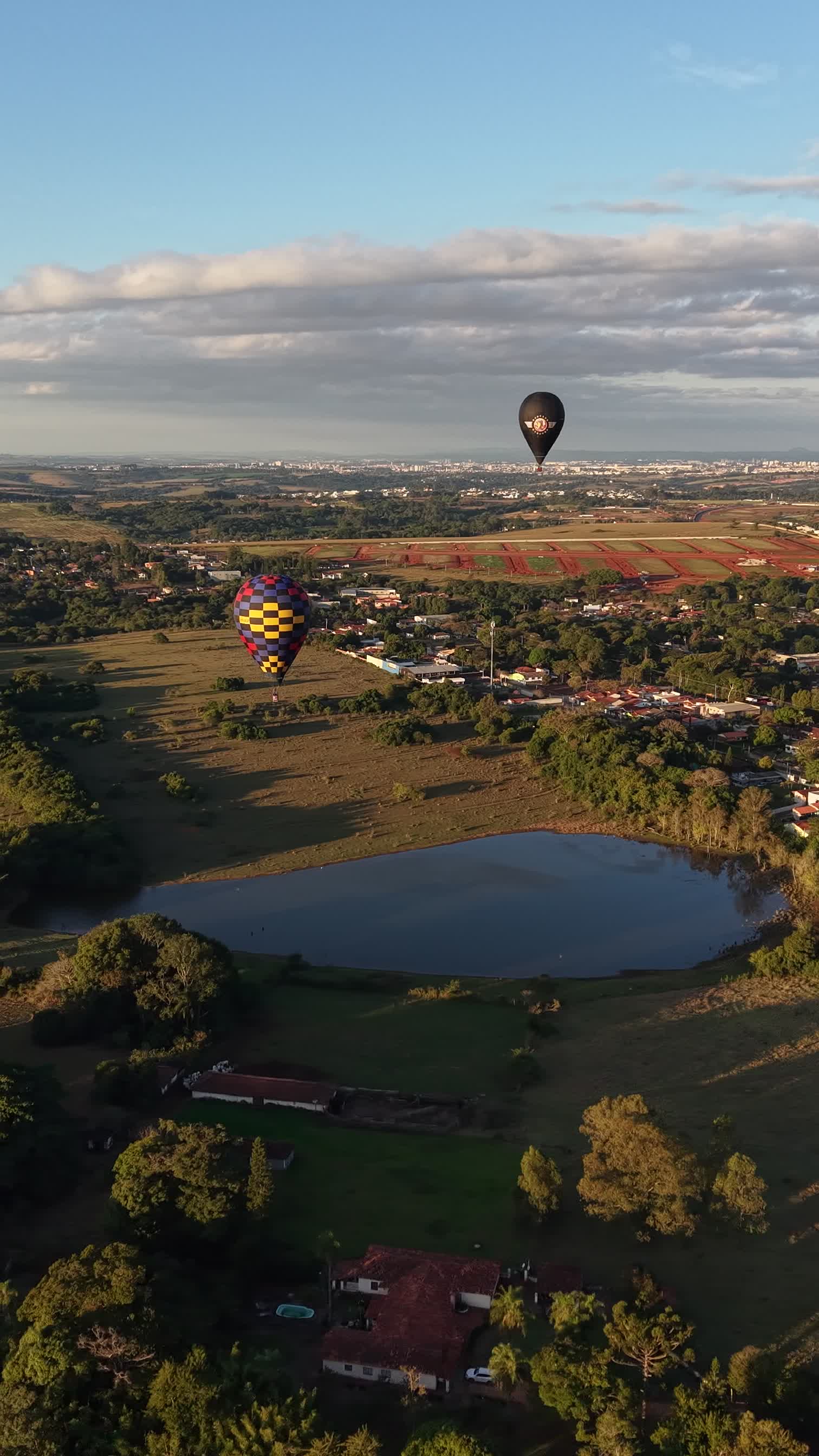 Balões coloridos sobre lago e paisagem rural