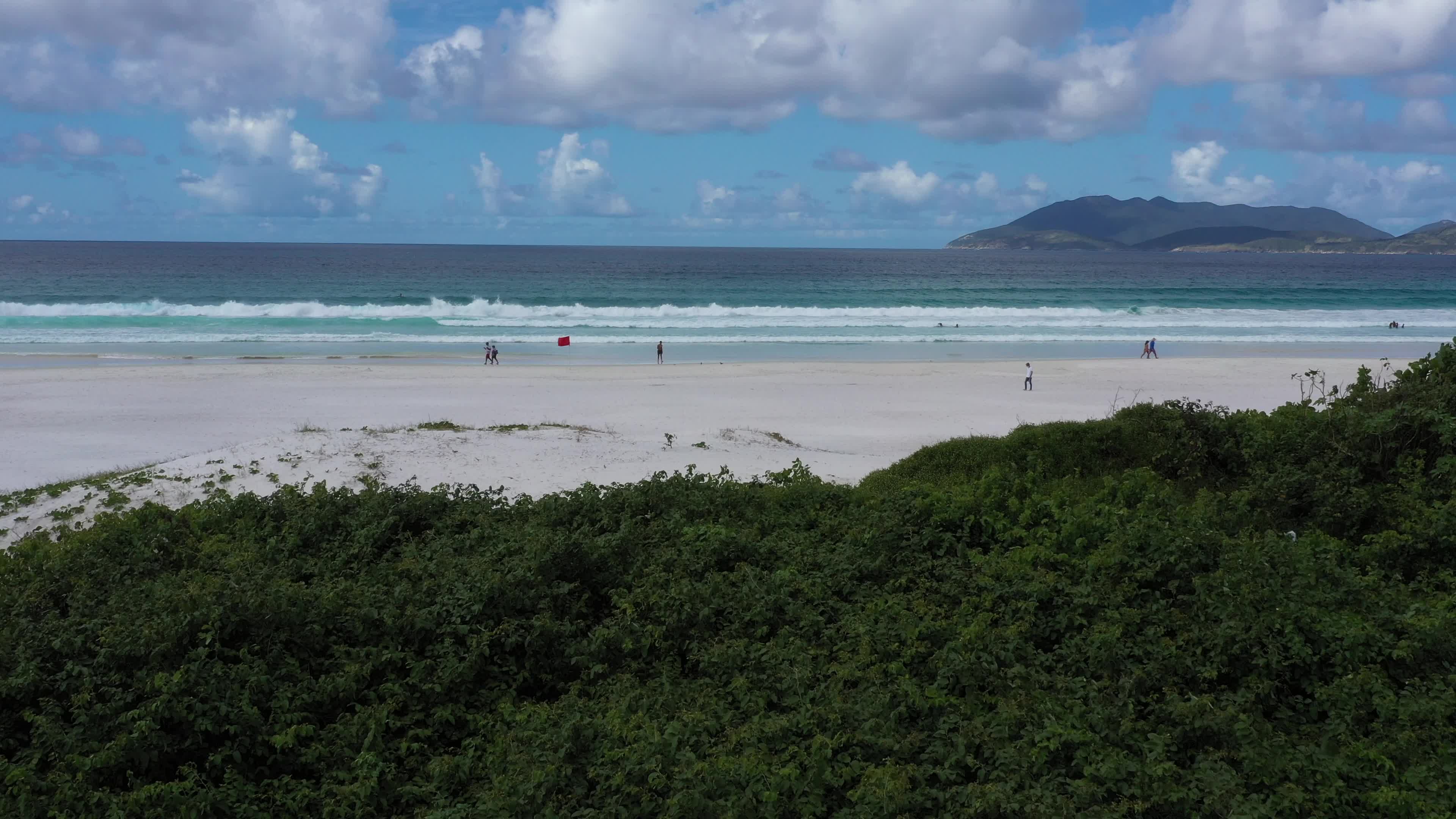 Drone baixo passa por cima de vegetação nativa e revela a Praia do Forte em Cabo Frio RJ