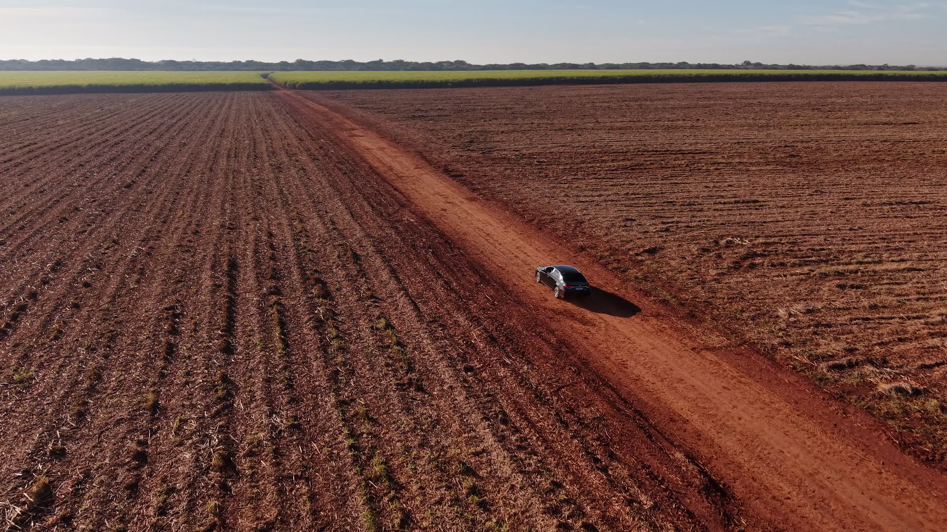 Carro solitário em estrada rural vermelha