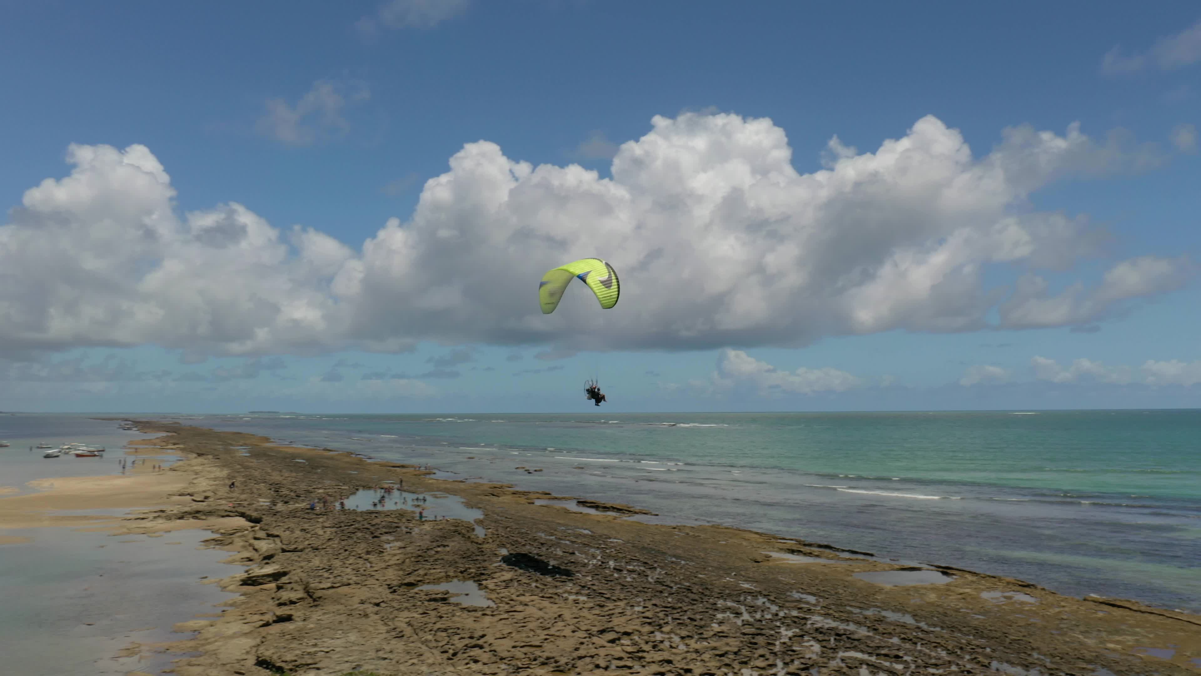 motorized paraglider flying low over the beach sand in Porto de Galinhas
